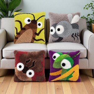 May include: Four square throw pillows featuring textured punch needle designs of insects. The top left is yellow with a brown beetle, top right is grey with a fly, bottom left is maroon with a brown beetle, and bottom right is purple with a green mantis.