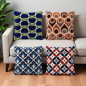 Peut inclure: Quatre coussins carrés avec une broderie texturée à l'aiguille. En haut à gauche, un motif floral bleu et vert. En haut à droite, un motif en forme de goutte marron et beige. En bas à gauche, un motif damassé bleu et blanc. En bas à droite, un motif géométrique circulaire rouge, bleu et blanc.