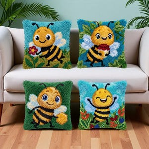 May include: Four square throw pillows featuring punch needle embroidery of cartoon bees. Each pillow displays a yellow and black striped bee with blue wings against colorful backgrounds of flowers, greenery, and honeycomb patterns.