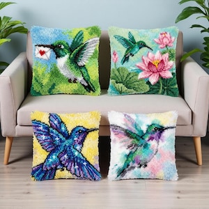 Può includere: Quattro cuscini quadrati decorativi con disegni di colibrì. I cuscini presentano colori vivaci e dettagliati punti a croce. Uno mostra un colibrì che trasporta una lettera, un altro con un fiore di loto e due con colibrì in volo.