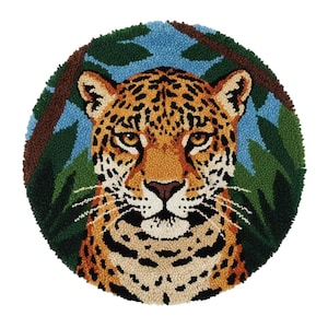 May include: A circular rug with a hand-tufted design of a jaguar's face. The jaguar has a tan coat with black spots, a brown nose, and yellow eyes. The background features blue sky, green leaves, and brown tree branches.