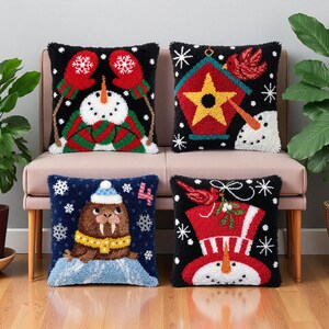 May include: Four square throw pillows with textured punch needle designs. One features a snowman with red mittens, another a birdhouse with a star, a third a walrus with a yellow scarf and the number 4, and the last a snowman in a top hat.
