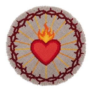 Peut inclure: Tapis rond gris avec un cœur rouge et des flammes, entouré de rayons jaunes et d'une couronne d'épines rouge foncé. Le tapis a un aspect texturé et fait à la main, avec un design circulaire. C'est un objet décoratif.