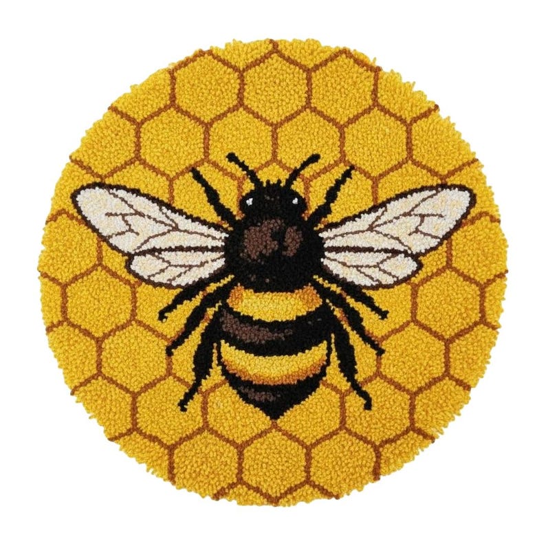 May include: A round, yellow rug with a bee design. The bee is black and yellow with white wings, centered on a honeycomb pattern. The rug is made of a textured material, likely wool or a similar fiber.