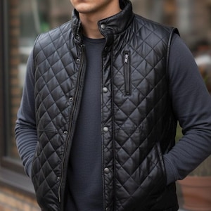 Könnte beinhalten: Schwarze, gesteppte Lederweste mit Stehkragen und Reißverschluss. Die Weste hat ein Rautenmuster und zwei Seitentaschen. Die Weste wird über einem dunkelgrauen Langarmshirt getragen.