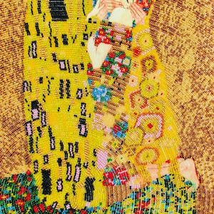 K&ouml;nnte beinhalten: Ein Perlenkunstwerk, das Gustav Klimts "Der Kuss" darstellt. Das Bild zeigt zwei sich umarmende Figuren, wobei der Kopf des Mannes mit gr&uuml;nem Laub geschm&uuml;ckt ist. Das Kunstwerk wird von Gold-, Gelb- und Blumenmustern dominiert.