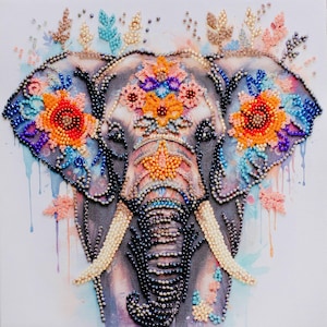 Op de afbeelding: Een wandkunstwerk met kralen dat een gestileerde olifantenkop toont, versierd met levendige oranje, blauwe en paarse bloemmotieven. Het ontwerp bevat ingewikkeld kraalwerk op de oren, het voorhoofd en de slurf tegen een aquarelachtergrond.