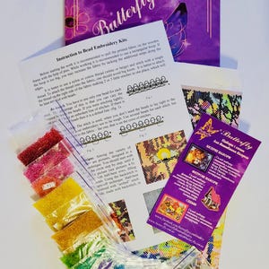 K&ouml;nnte beinhalten: Perlenstick-Set mit Anleitung und einer lila Verpackung mit der Aufschrift "Butterfly". Das Set enth&auml;lt kleine Beutel mit bunten Perlen, ein gedrucktes Muster und ein Faltblatt mit Diagrammen. Das Set ist f&uuml;r die Perlenstickerei konzipiert.