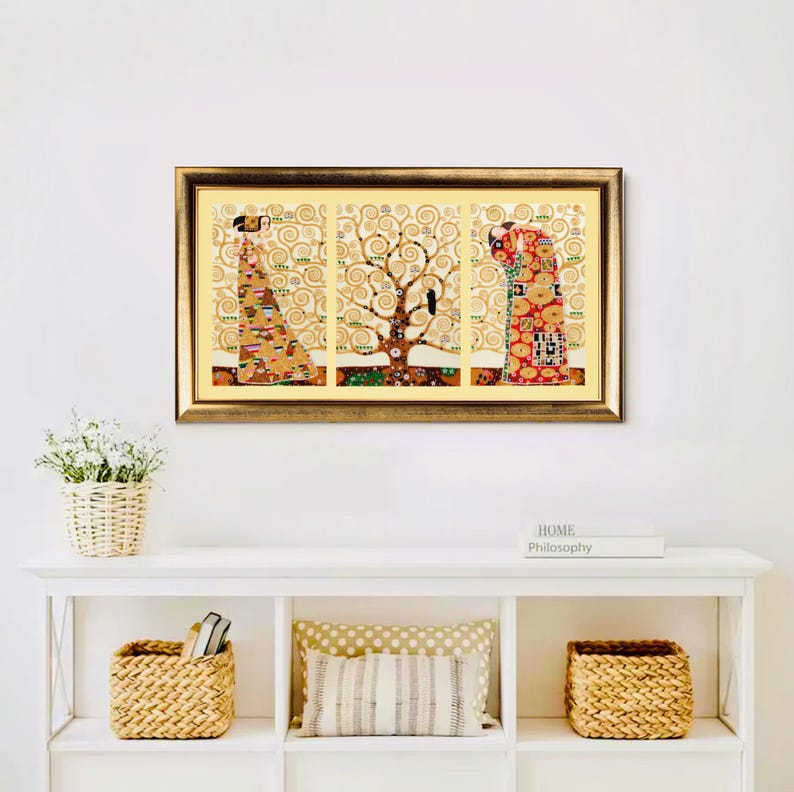 K&ouml;nnte beinhalten: Ein gerahmter Triptychon-Kunstdruck mit einem goldfarbenen Kunstwerk mit einem Baum und Figuren. Das Kunstwerk befindet sich in einem goldenen Rahmen und wird &uuml;ber einem wei&szlig;en Regal mit dekorativen Gegenst&auml;nden ausgestellt.
