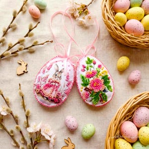 May include: A white ceramic mug with a black handle and the text "But First, Coffee" in a bold, black font. The mug is set against a blurred background, suggesting a cosy setting.