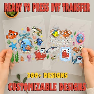 May include: Two clear sheets with colorful cartoon images of characters from the movie Finding Nemo. The sheets are held by hands. Text at the top reads "READY TO PRESS DTF TRANSFER". The bottom text says "300+ DESIGNS CUSTOMIZABLE DESIGNS".