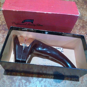 May include: A black and brown knife sharpener in its original box. The box is red and has the text "CUICO Professional Honing Stone" printed on it. The sharpener has a handle and a wheel for sharpening knives.