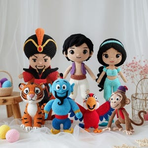 May include: A collection of handmade crochet dolls featuring characters from the animated film Aladdin. The dolls include Aladdin, Jasmine, Jafar, Genie, Abu, Iago, and Rajah, each with distinct colors and features. The dolls are arranged on a white surface.