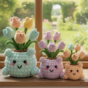 Op de afbeelding: Drie gehaakte tulp bloempotten in pastelkleuren staan op een houten vensterbank. De potten zijn lichtblauw, lavendel en perzik, elk met een lachend gezicht en kleine armen. De tulpen zijn in tinten perzik, geel, blauw en roze.