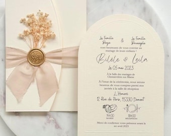 May include: Ivory wedding invitation with a dried flower bouquet, a gold wax seal, and a blush ribbon. The invitation includes the names Bilele & Leila, the date May 5, 2023, and other details in French.