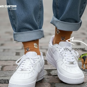 May include: A pair of white sneakers with brown socks featuring dog faces. The socks are visible beneath rolled-up blue jeans. The image includes the text "Your pets!" and "BROWN". The brand name "PAWS CUSTOM Studio" is also visible.
