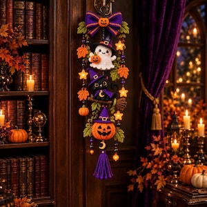 May include: A vertical crochet wall hanging featuring a purple bow at the top, a white ghost wearing a witch hat, a black cat on a broomstick, and a jack-o'-lantern at the bottom. The piece is decorated with orange leaves, small pumpkins, and stars.