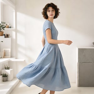 Pu&ograve; includere: Un vestito azzurro con maniche corte e gonna a balze. L'abito ha un corpetto aderente e una gonna ampia e svasata. Il tessuto sembra essere lino o cotone leggero, adatto al clima caldo. L'abito &egrave; in tinta unita, senza motivi visibili.