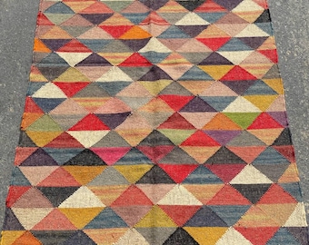 May include: A rectangular, multi-colored rug with a geometric diamond pattern. The rug features a variety of colors including red, yellow, blue, and black. The rug has a black border with fringe.