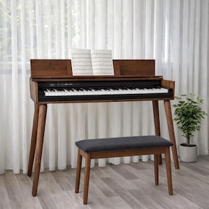 May include: A wooden digital piano with a black and white keyboard, music sheets, and a matching bench. The piano has a dark brown finish and is set against a white curtain backdrop. A small potted plant is to the right.