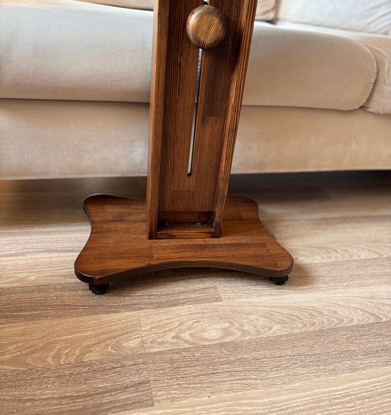 May include: A wooden floor lamp with a dark brown finish. The lamp has a rectangular column with a decorative wooden knob and a square base. The lamp is on a hardwood floor.