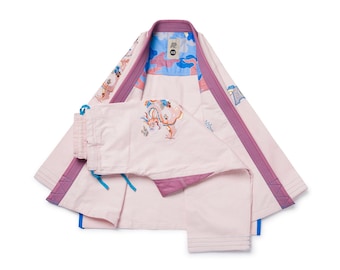 May include: A light pink martial arts uniform with purple trim and embroidered details. The uniform includes a jacket and pants, with a blue and patterned interior. The jacket has a collar and the pants have a drawstring.