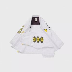 Puede incluir: Uniforme blanco de Jiu-Jitsu con detalles en negro y amarillo. La chaqueta tiene texto amarillo en las mangas y los hombros. Los pantalones presentan tres emblemas circulares amarillos y negros. El uniforme está sobre un fondo blanco.