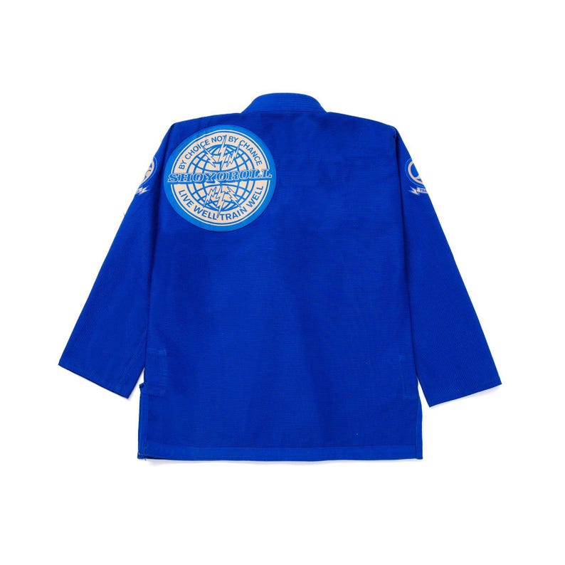 May include: A royal blue martial arts uniform, or gi, with long sleeves. The back features a circular emblem with the text "BY CHOICE NOT BY CHANCE" and "LIVE WELL TRAIN WELL". The gi is designed for training and competition.