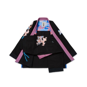 Puede incluir: Uniforme de artes marciales negro con detalles rosas y azules. La chaqueta y el pantalón presentan diseños de dragones bordados. El cuello y el ribete son rosas, con detalles azules. El forro interior tiene un patrón de camuflaje azul y rosa.
