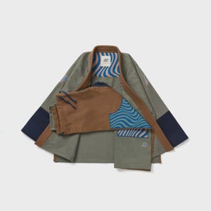 May include: A two-piece olive green and brown martial arts uniform set. The jacket has brown trim and navy blue patches. The trousers are brown with a drawstring. The uniform has blue wave pattern accents and a logo.