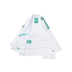 Könnte beinhalten: Weißer Kampfsportanzug mit türkisfarbenen Akzenten. Der Anzug besteht aus Jacke und Hose mit türkisfarbenen Logos und Verzierungen. Die Jacke hat einen Kragen und ist offen, wodurch das Innere sichtbar wird. Der Anzug liegt auf weißem Hintergrund.