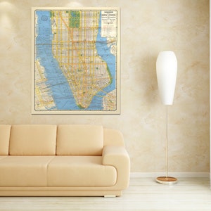 Puede incluir: Un mapa vintage de la ciudad de Nueva York con un fondo beige y elementos de agua azules. El mapa está enmarcado y colgado en una pared beige sobre un sofá beige claro.