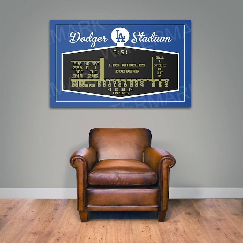Puede incluir: Un marcador de estilo vintage con fondo azul y una pantalla negra que muestra el marcador de un partido de b&eacute;isbol entre los Cubs y los Los Angeles Dodgers. El marcador tambi&eacute;n muestra la hora, 7:51, y el n&uacute;mero de bolas, strikes y outs. El marcador est&aacute; colgado en una pared con un sill&oacute;n de cuero marr&oacute;n delante.