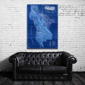 May include: A vintage blue and white map of San Mateo County, California. The map shows the county's roads, rivers, and towns. The map is framed and hanging on a white brick wall.