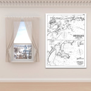 May include: A black and white nautical chart of Marblehead, Salem, Beverly, Manchester, and Magnolia, Massachusetts. The chart includes detailed coastlines, navigational markers, and text labels. The chart is displayed on a white wall.
