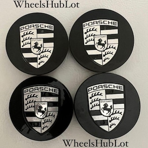 May include: Four black Porsche wheel center caps. Each cap features the Porsche emblem in white and silver, with the word "PORSCHE" above and "STUTTGART" below. The text "WheelsHubLot" is also visible.