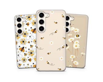 May include: Three phone cases with floral and bee designs. One case features a white background with yellow daisies and bees. Another has a beige background with bees and small white flowers. The third case has a beige background with white daisies.