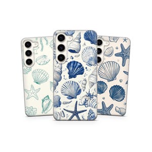 Puede incluir: Tres fundas para teléfono con diseño de conchas marinas. Las fundas presentan una variedad de conchas y estrellas de mar en tonos azules y turquesas sobre un fondo crema. Las fundas son para un smartphone.