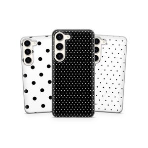 May include: Three phone cases with a polka dot pattern. One case is black with white dots, and the other two are white with black dots. The cases have camera cutouts and are designed for a smartphone.