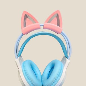 May include: A set of headphones in pastel colours, featuring cat ears. The ear cups are light blue, the headband is pale blue, and the cat ears are pink with a silver interior.