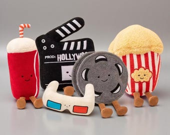 May include: A collection of plush movie-themed toys. Includes a red soda cup with a straw, a black clapperboard with "HOLLYWOOD" text, a film reel, 3D glasses, and a popcorn container with red and white stripes.