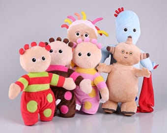 May include: A group of six plush toys in various colors. The toys have large, round eyes and are wearing outfits with stripes and polka dots. One is light blue, and another is tan. The toys are standing in a row.
