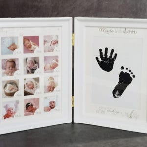 May include: A white, hinged picture frame with two panels. One panel displays nine baby photos, the other features a black handprint and footprint with the text "Made With Love". A perfect keepsake for new parents.