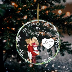 May include: A clear, round Christmas bauble with a gold string. The bauble features a couple embracing, with the text "THE YEAR I FOUND MY Missing Piece". Includes snowflakes, a heart-shaped puzzle, and the year 2025.