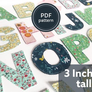 Puede incluir: Conjunto de letras de tela, cada una de 7,6 cm de alto, con diseños florales en varios colores. Las letras están cortadas y cosidas, con un borde festoneado. Un gráfico circular dice "PDF pattern".