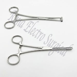 Puede incluir: Dos pinzas hemostáticas quirúrgicas de acero inoxidable se muestran sobre un fondo blanco. Las pinzas hemostáticas tienen mangos de anillo y mecanismos de bloqueo. El texto "Rina Electro Surgical" es débilmente visible en el fondo.