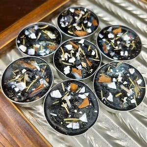 May include: Seven black tea light candles with white, brown, and yellow accents. The candles are arranged in a tray with a wooden frame. The candles have a decorative design.