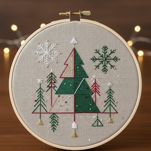 Può includere: Un telaio da ricamo a punto croce con un disegno di albero di Natale. Il disegno comprende alberi verdi e rossi, fiocchi di neve bianchi e dettagli dorati su un tessuto beige. Il ricamo è in un telaio rotondo di legno.