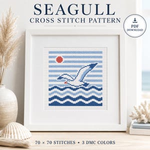 Puede incluir: Un marco blanco cuadrado que contiene un patrón de punto de cruz de una gaviota volando sobre agua azul ondulada con un sol rojo contra un cielo de rayas azul claro. El texto SEAGULL CROSS STITCH PATTERN y PDF DOWNLOAD es visible arriba.