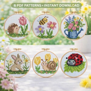 Può includere: Sei schemi a punto croce in cerchi di legno, ognuno con un diverso design a tema primaverile. I disegni includono un riccio, un'ape, fiori, un coniglietto, una lumaca e una coccinella. Il testo "6 PDF PATTERNS • INSTANT DOWNLOAD" è in alto.